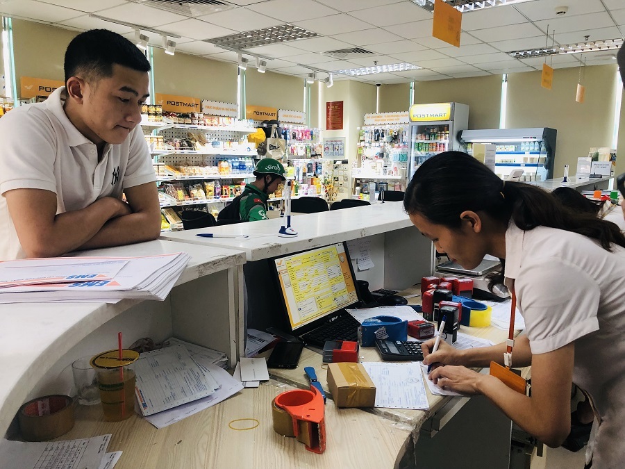  Tại quầy giao dịch của Bưu điện Việt Nam, nhân viên kiểm tra kỹ hàng trước khi gói bọc và tính cước.